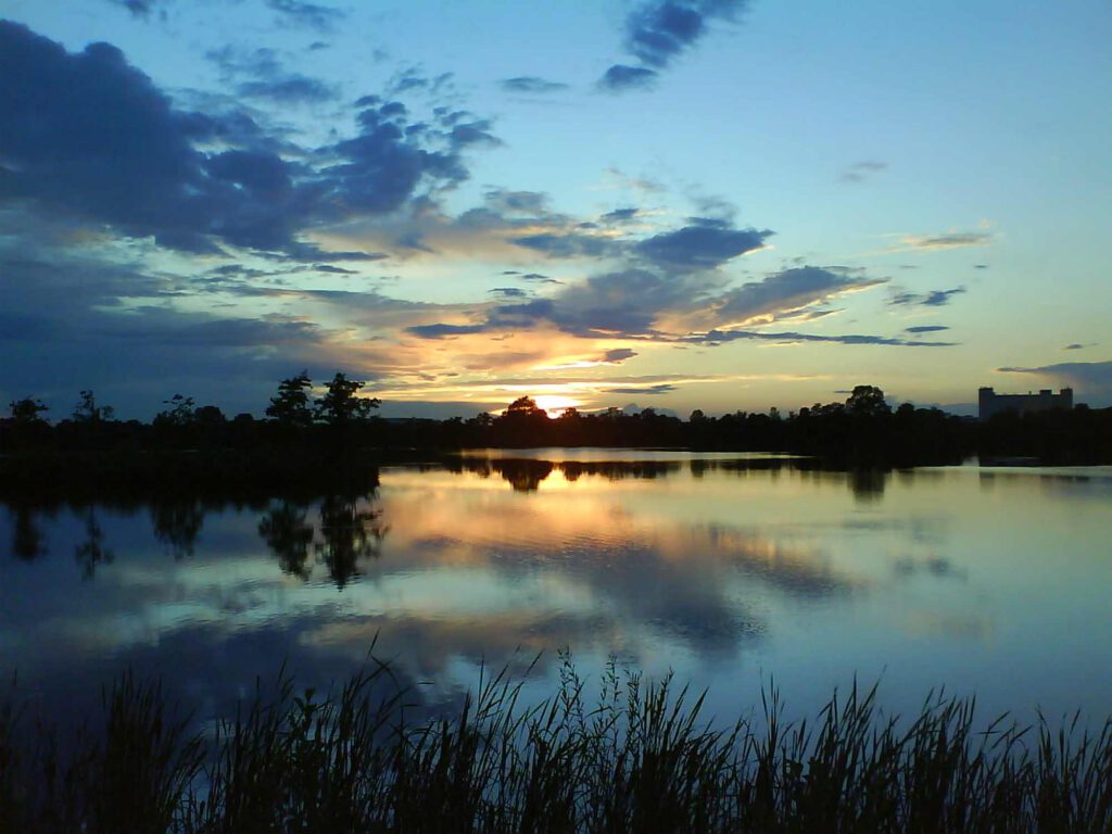 Abendstimmung am See mit blauem Himmel und untergehender Sonne.